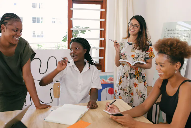 Women at work with notepads laughing and smiling around table