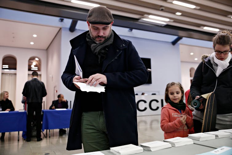 Dans un bureau de vote à Lille en 2017, des électeurs choisissent prennent les bulletins de vote