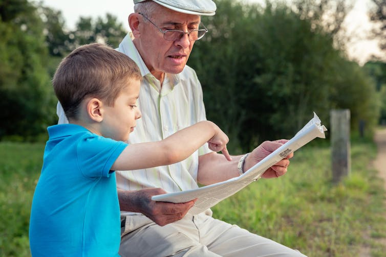 Un enfant lisant le journal avec son grand-père