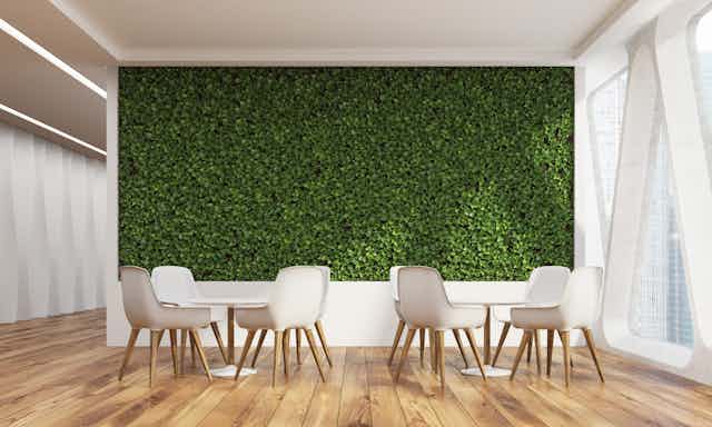 Un espace de détente avec un mur végétal, un parquet en bois et des meubles clairs