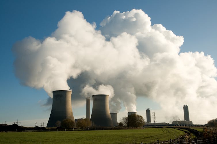 nuclear power station with huge white clouds of smoke, blue sky