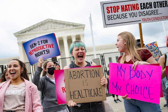 Abortions rights advocates hold signs and chant in front of the Supreme Court building.