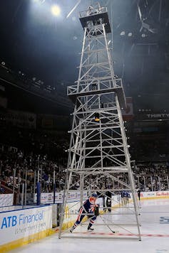 A man in hockey gear skates under a metal structure designed to look like an oil machine.