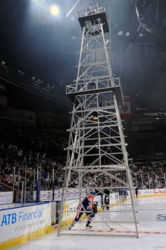 A man in hockey gear skates underneath a metal scaffold meant to look like oil machinery.