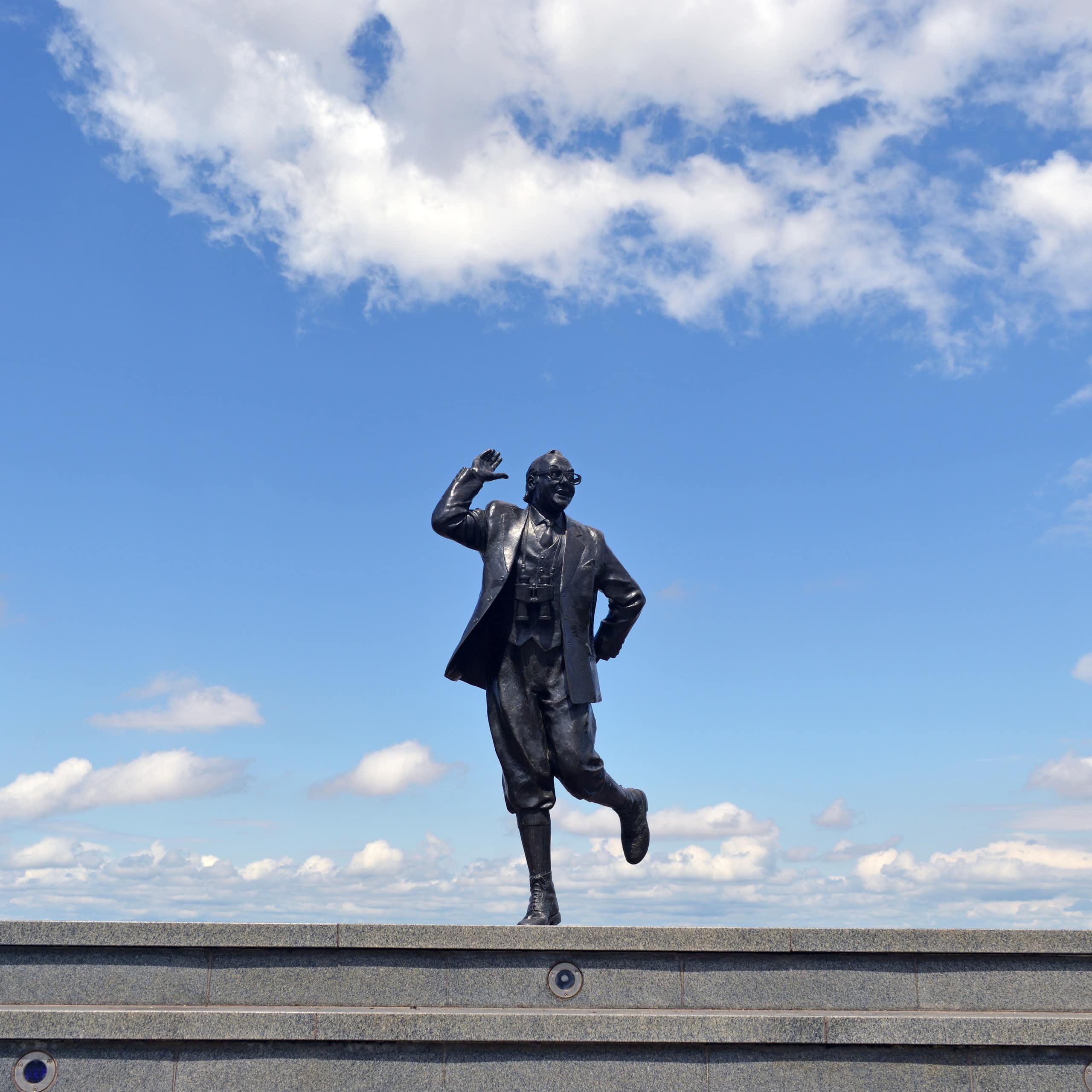 A statue of Eric Morcambe against a blue sky