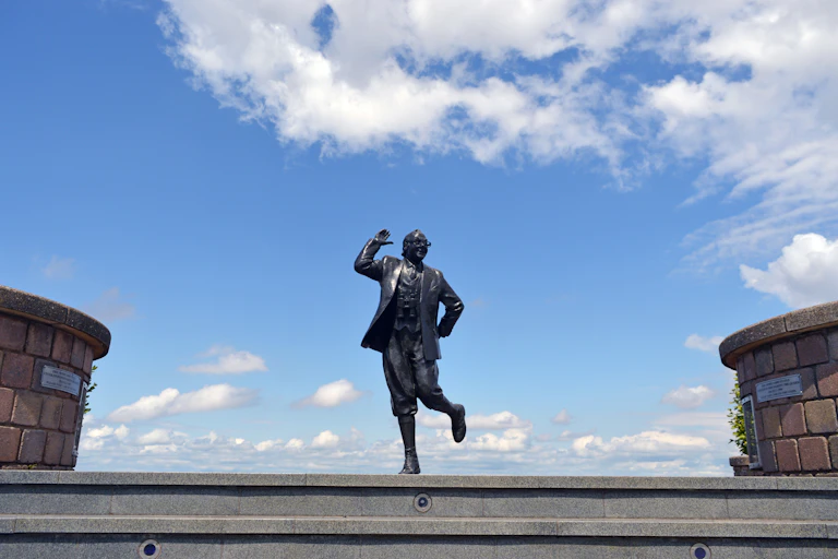 A statue of Eric Morcambe against a blue sky