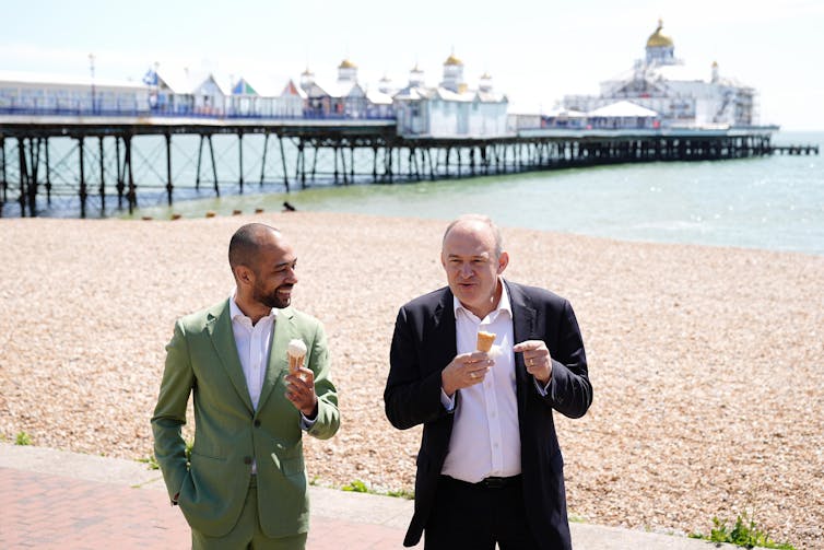 Ed Davey e Josh Babarinde tomando sorvete em frente ao cais de Eastbourne