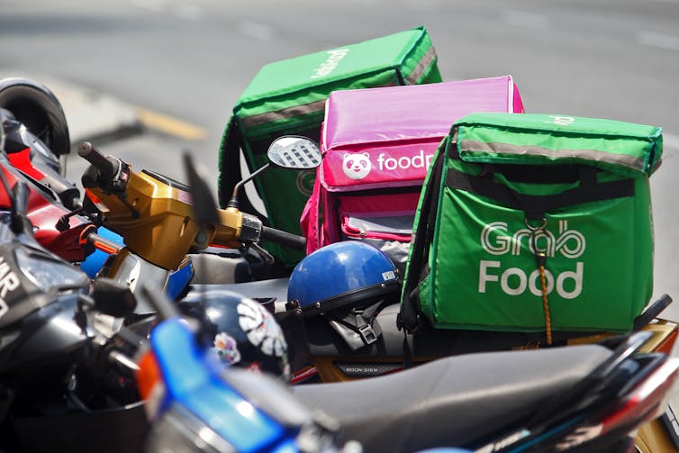 A row of parked bikes with food delivery bags strapped to the back