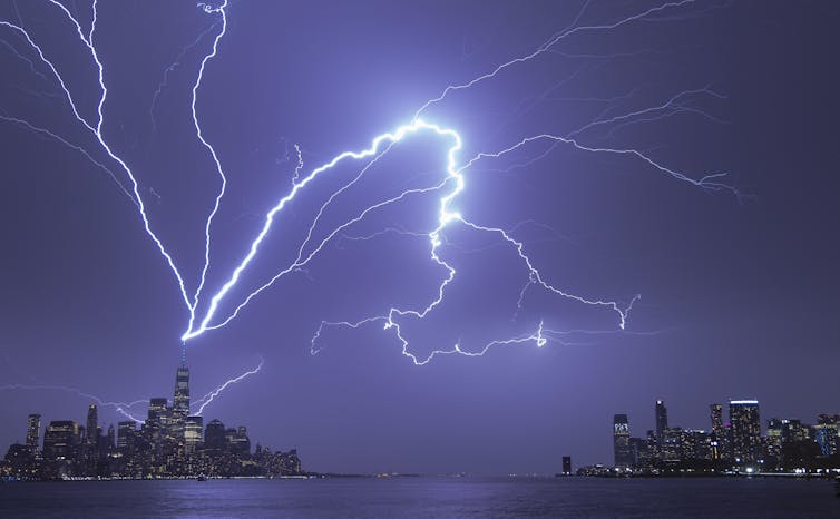A vibrant display of lightning striking the tall tower and zigzagging through the sky.
