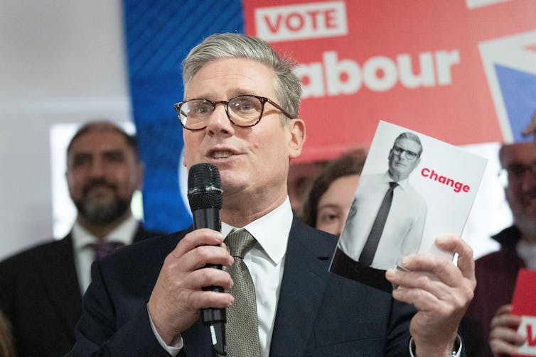 Keir Starmer segurando uma cópia do manifesto eleitoral do Partido Trabalhista de 2024.