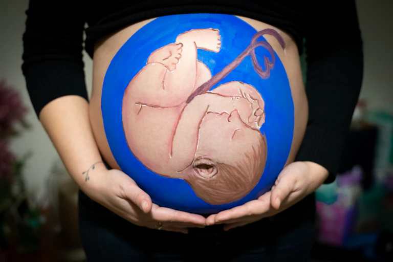 Baby painting on pregnant belly