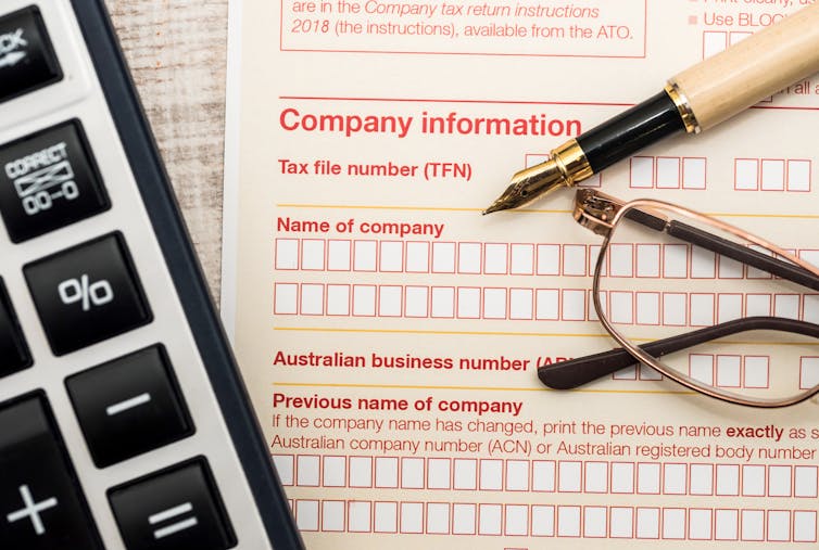A blank company tax return form, with calculator, pen, and glasses on top