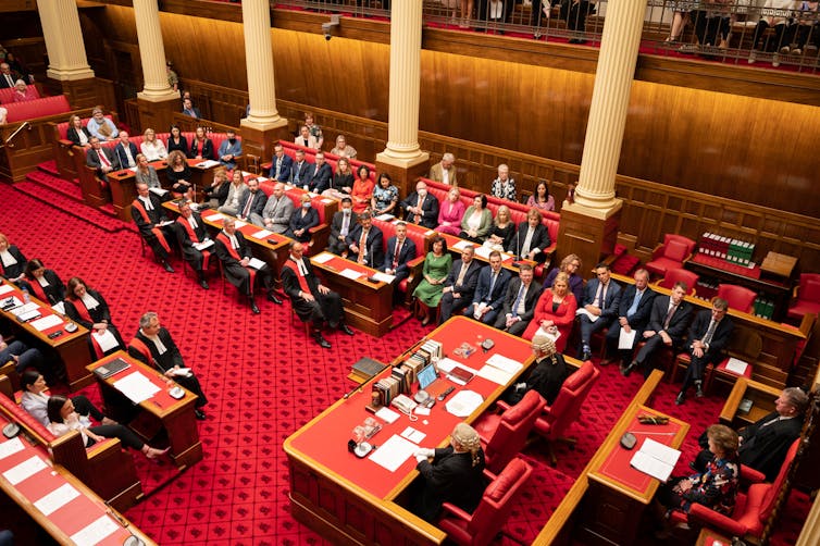 A red carpeted room from above with people sitting at desks