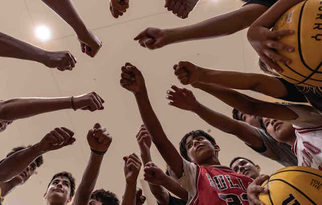 Young basketball players bump fists in a circle after a game