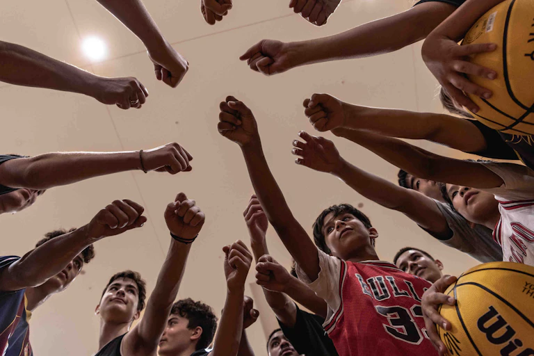 Young basketball players bump fists in a circle after a game