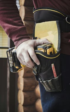 Closeup of man holding drill near belt