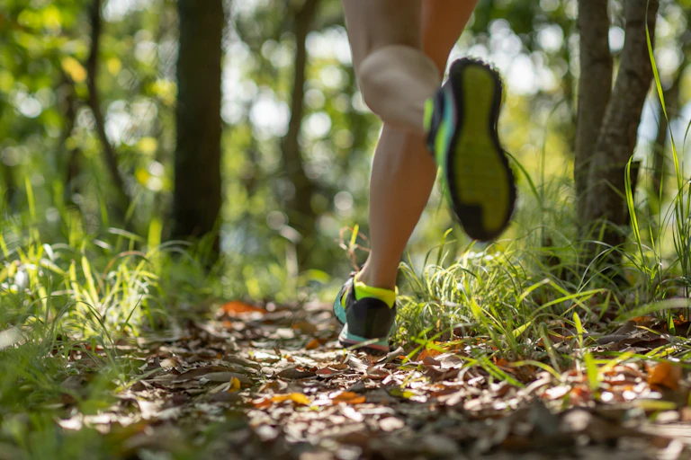 A female runner jogs along a forrest trail