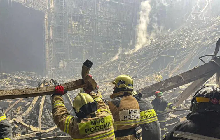Two rescue workers looking at debris from the terrorist attack in Moscow.