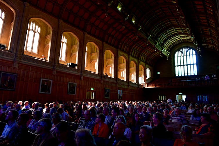 An audience sits in a large hall.