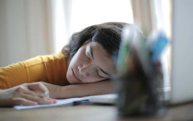 Young woman rests her head on a desk