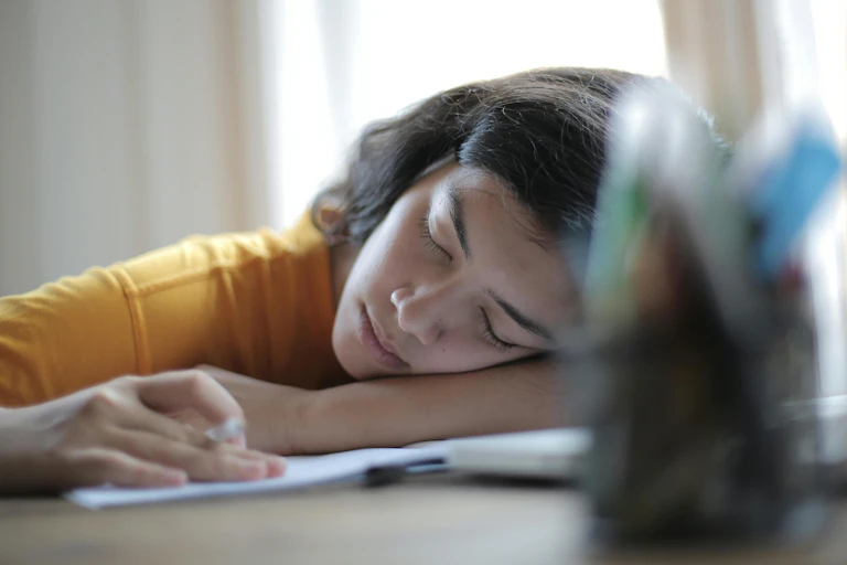 Young woman rests her head on a desk
