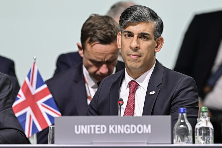 RIshi Sunak sitting behind a union flag and a label reading 'United Kingdom'/