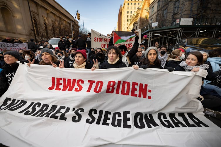 A large group of people holding a banner that says 'JEWS TO BIDEN: END ISRAEL'S SIEGE ON GAZA.'