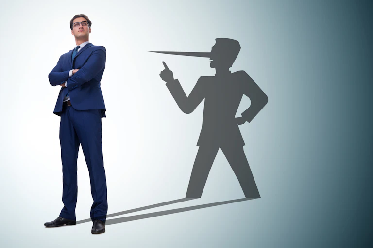 A man in a suit casts a shadow behind him and the shadow has a long nose.
