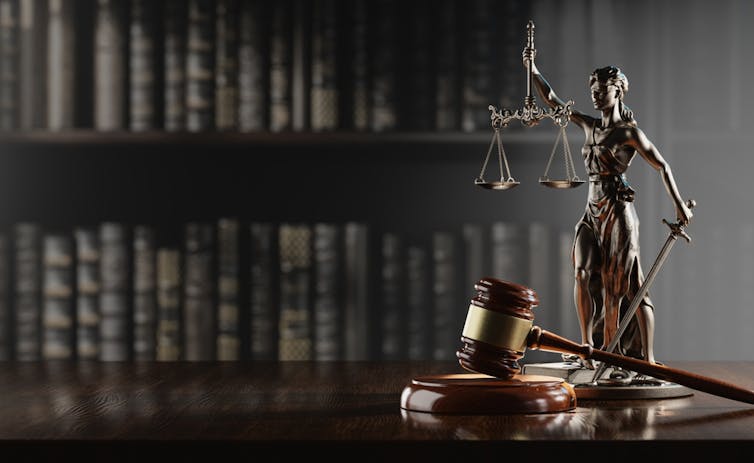 Themis, déesse de la justice, devant une bibliothèque