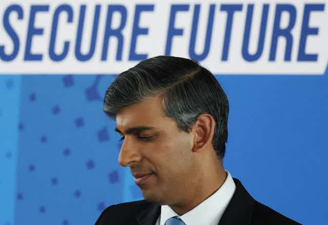 Rishi Sunak in front of a sign reading 'secure future'.