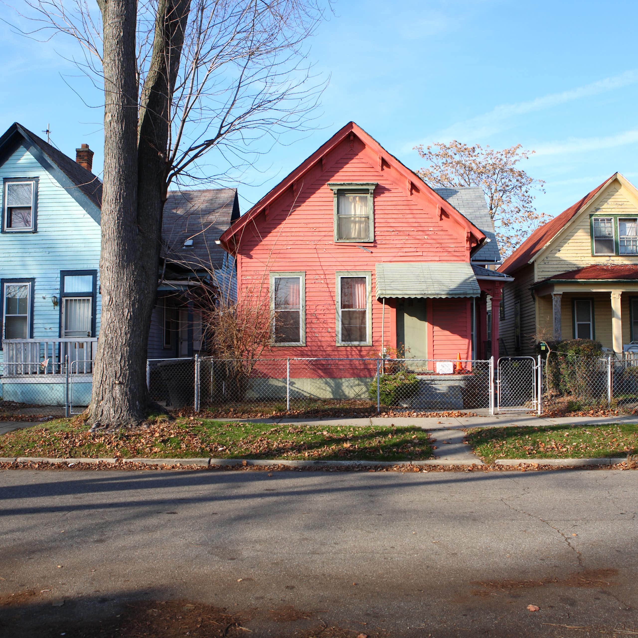 Multicolored 1920s-era rowhouses appear on a sunny day in Detroit.