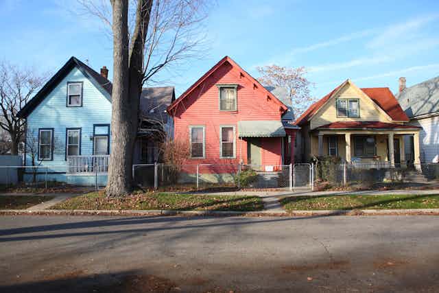 Multicolored 1920s-era rowhouses appear on a sunny day in Detroit.