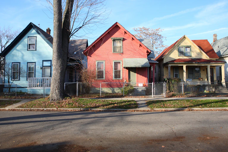 Multicolored 1920s-era rowhouses appear on a sunny day in Detroit.