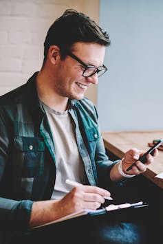 Man laughing while looking at phone screen