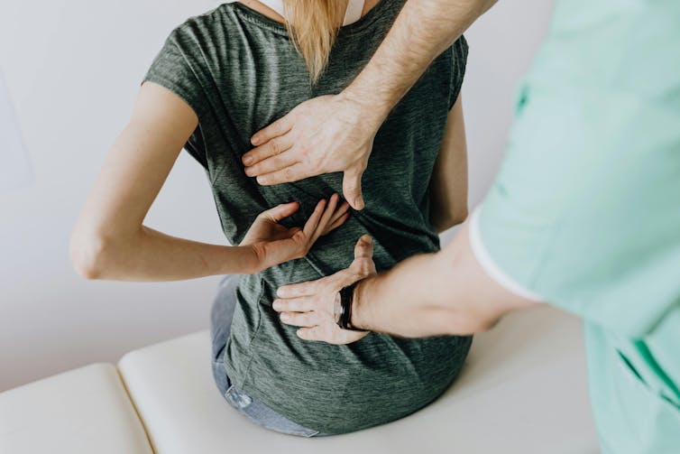 A health-care professional examines a woman's back.