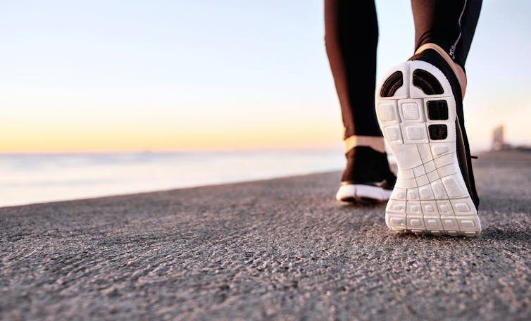 Two feet and lower legs in athletic gear walking alongside the water.