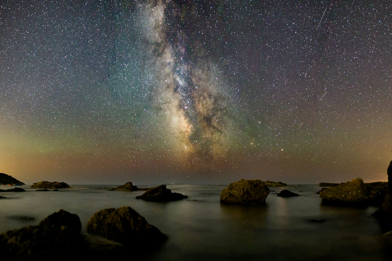 Photographie d'une nuit étoilée au dessus de l'eau.