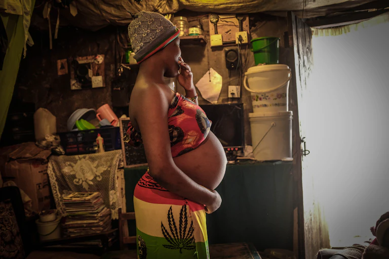A pregnant woman standing inside a dimly lit room