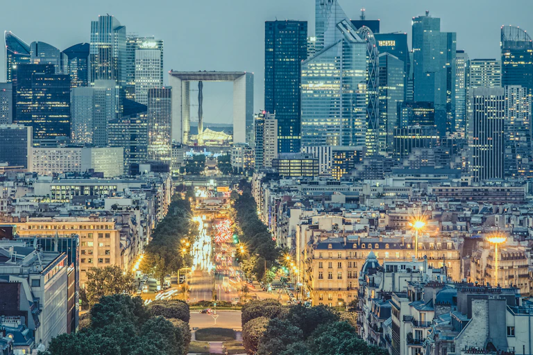 photo de la défense vue depuis Paris. fin de journée, avec des phares de voiture avenue charles de Gaulle à Neuilly au premier plan