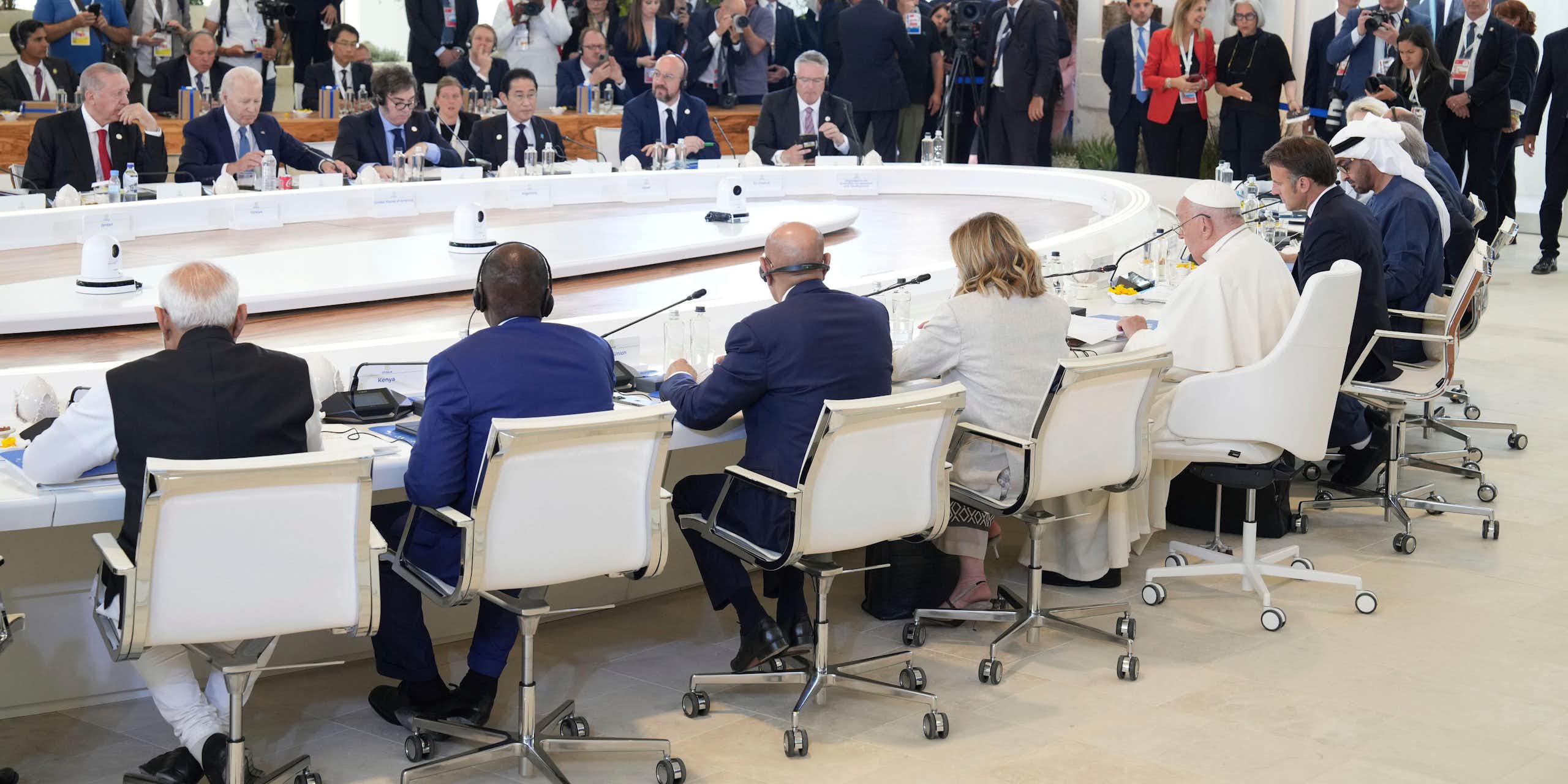 A group of leaders from G7 countries and other states sit around a big table with Pope Francis I