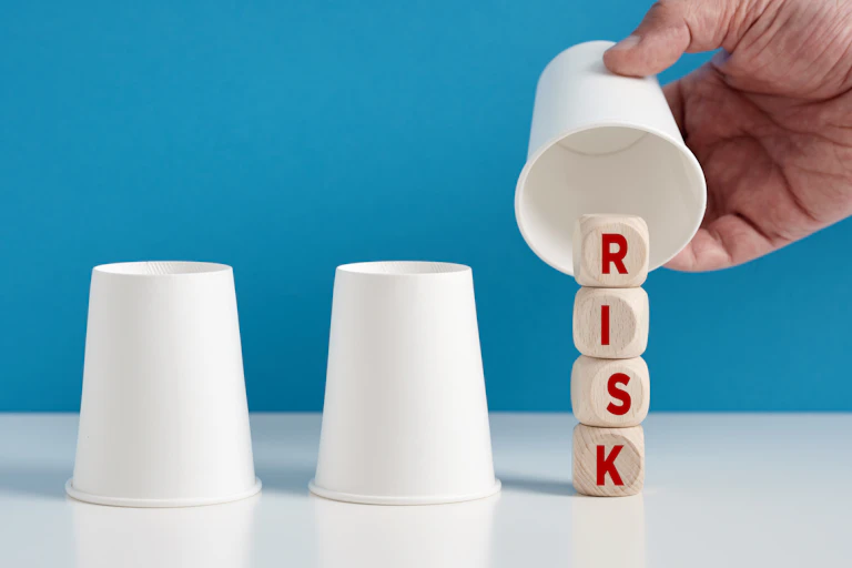 trois gobelets dont un soulevé avec des dés sur lesquels est écrit "risk"