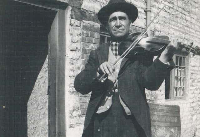 Black and white photo of a man playing a fiddle.