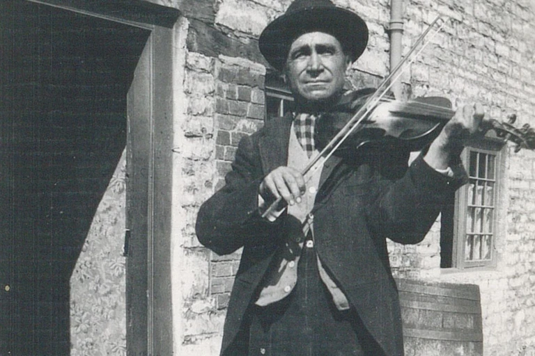 Black and white photo of a man playing a fiddle.