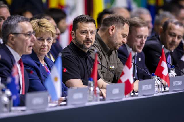 Ukrainian president |Volodymyr Zelensky sits at a long table flanked by representatives from several other countries including Switzerland.