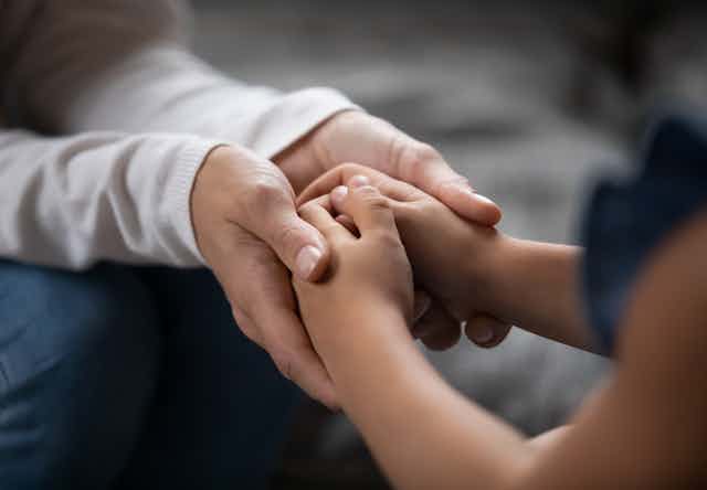 Adult hands holding a child's hands