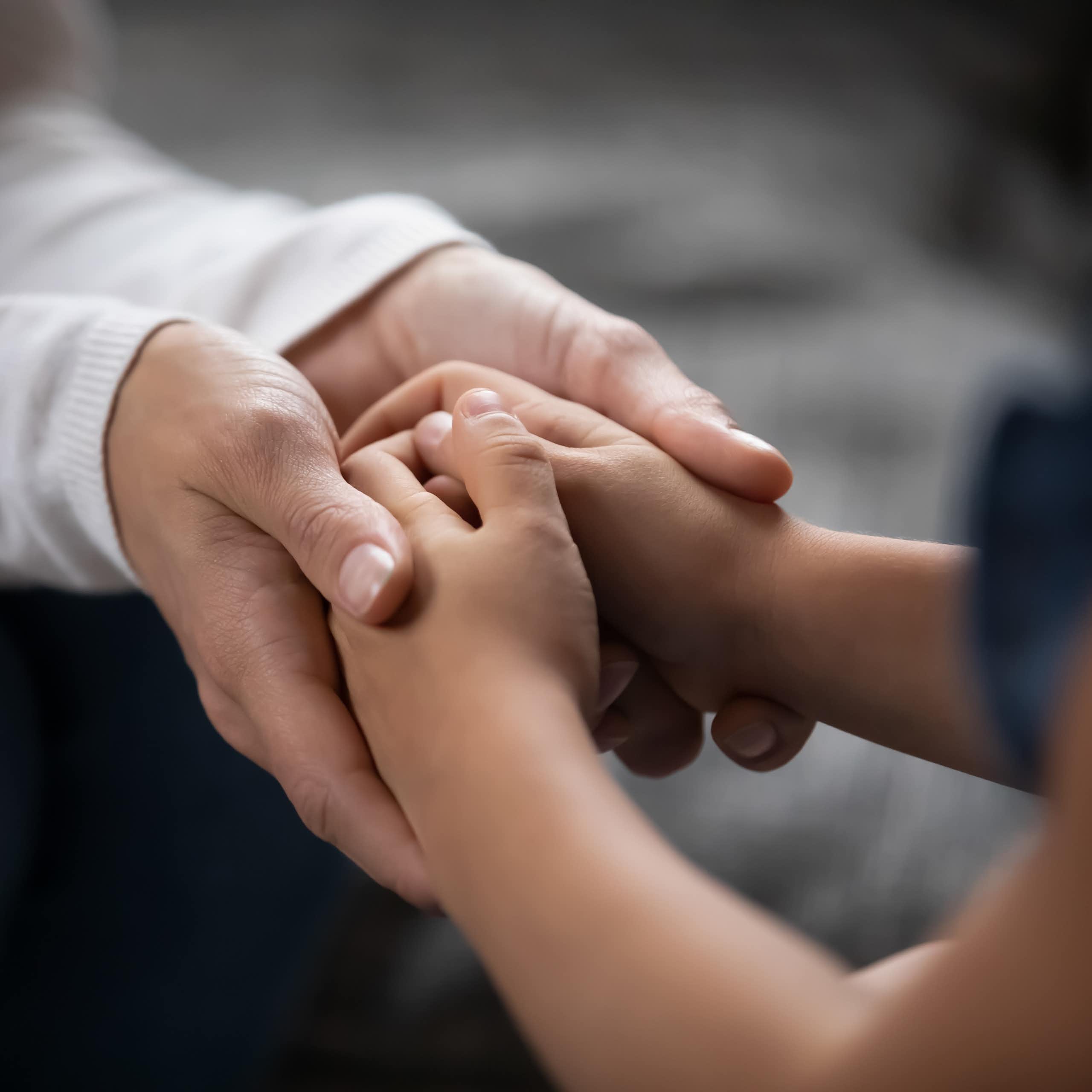 Adult hands holding a child's hands