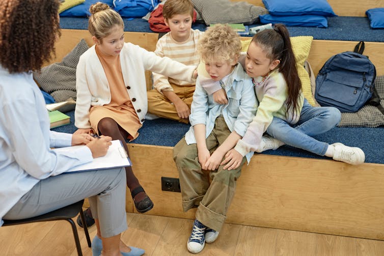 An adult holding a clipboard with four children