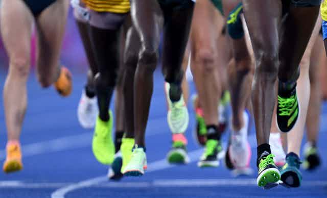 Diversas pernas de atletas numa pista de corrida durante a final feminina dos 10.000 m nos Jogos da Commonwealth de 2022