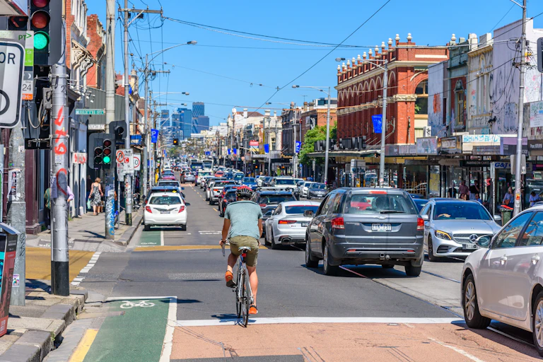 Cars and a bike travel down Sydney Road in Melbourne.