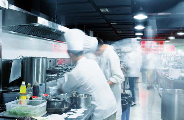 Busy chefs seen blurred working in a commercial kitchen